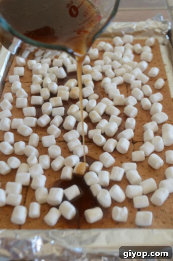 A photo showing a baking pan with graham crackers, marshmallows, and freshly poured caramel syrup