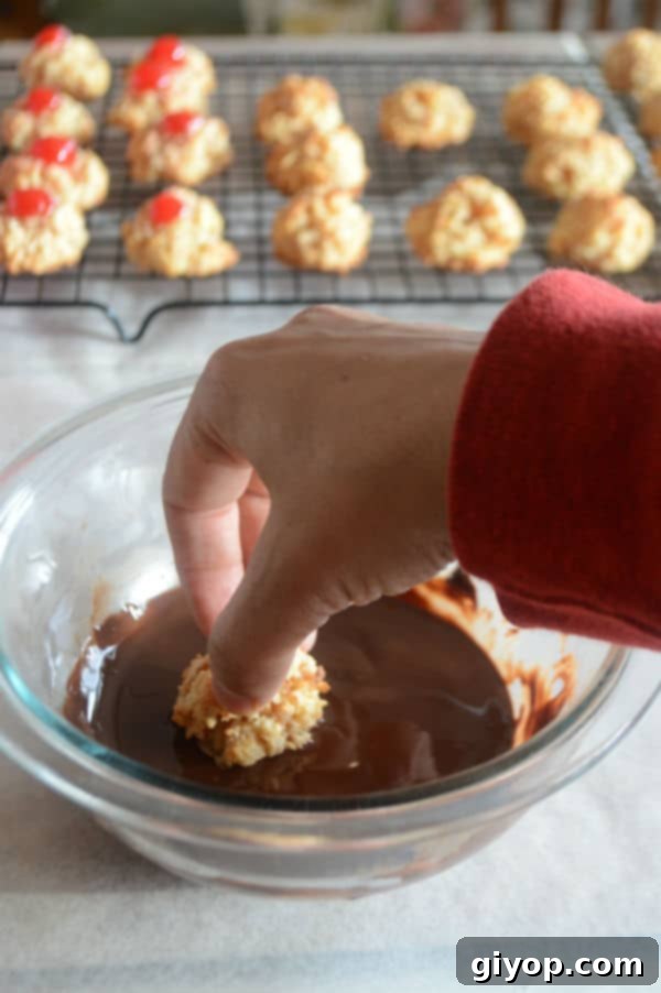 A bowl of food on a plate, with hand mixing Macaroon in chocolate, illustrating the final step of decorating macaroons with melted chocolate.