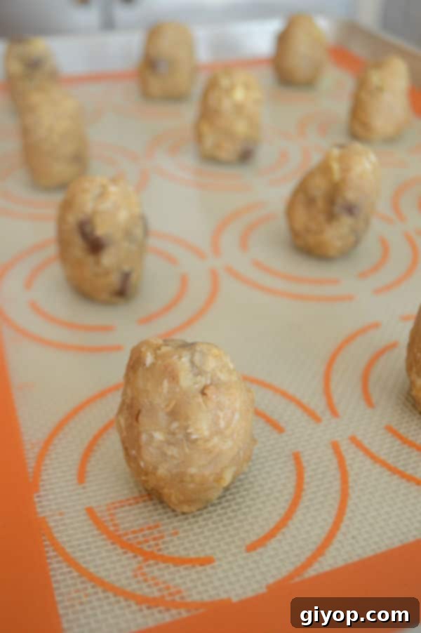 Portioned cookie dough balls arranged on a baking sheet lined with parchment paper, spaced evenly apart