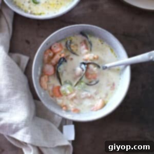 A top view of a bowl with creamy seafood soup and a spoon in it, ready to be eaten.