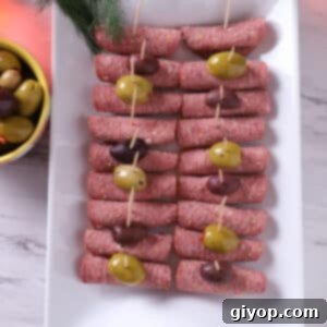 A top view of a white tray with salami roll ups, perfect for an appetizer spread.