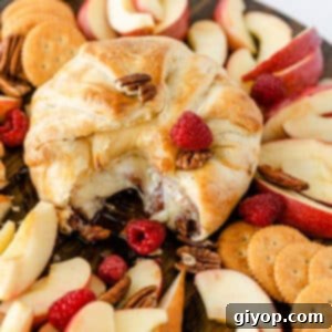 Baked brie with puff pastry with jam and raspberries oozing out of center.