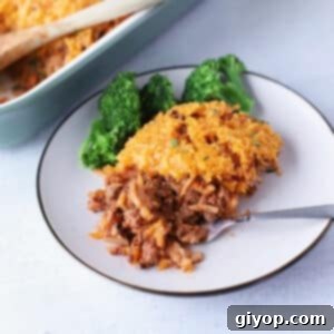 Hearty Ground Beef and Hashbrown Bake 2 Hamburger Hashbrown Casserole on a white background with green herbs.