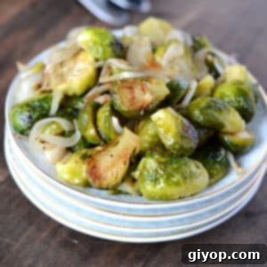 A close up image of roasted Brussels sprouts on a stack of white dishes, ready to be served.