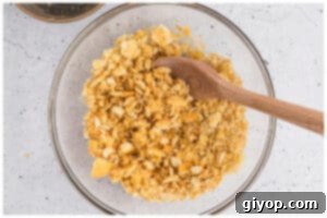 Crushed buttery crackers thoroughly mixed with melted butter in a glass bowl.