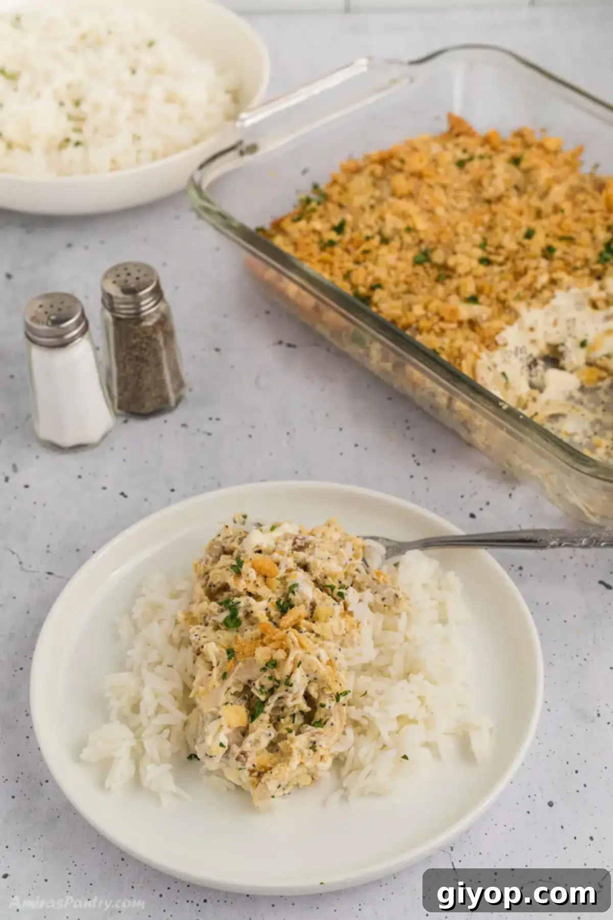 A serving of poppyseed chicken casserole on a white plate, garnished with fresh herbs, ready to be eaten.