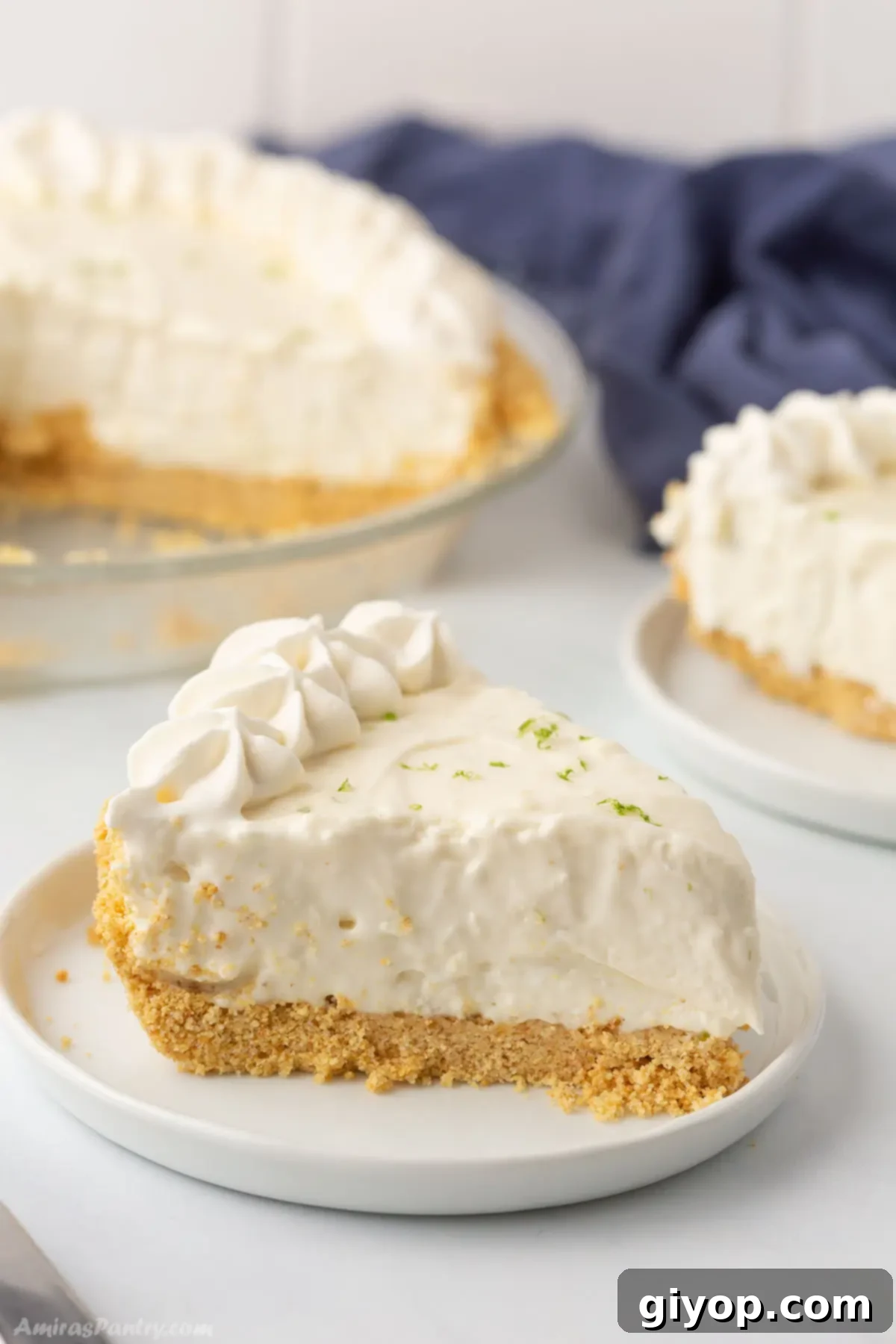 A side view of a slice of key lime pie on a white plate, showcasing its creamy texture and golden crust.