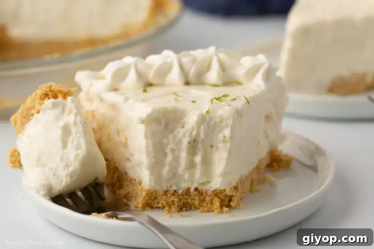 A close-up view of a wedge of key lime pie on a white plate, with a small portion already enjoyed.