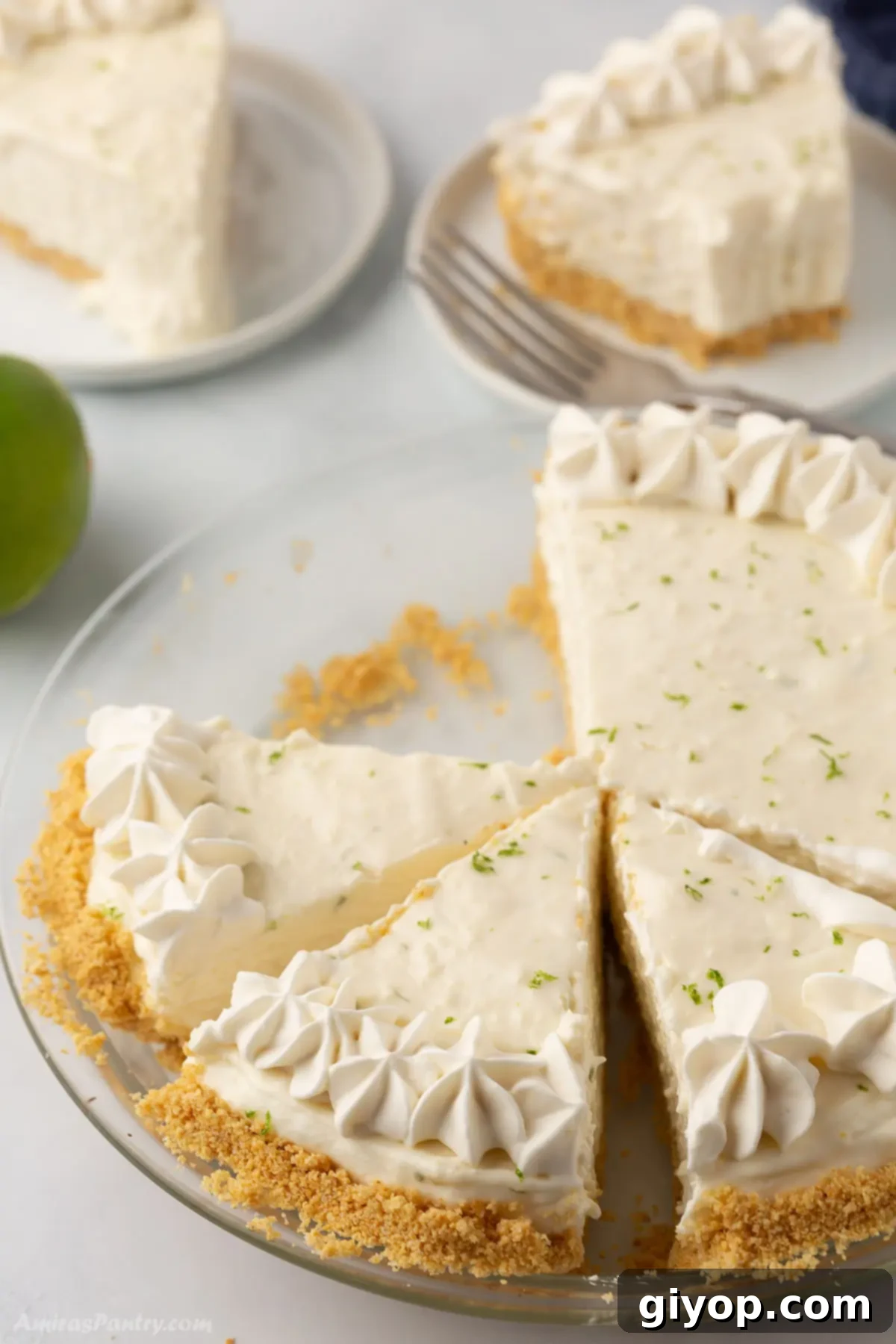 A whole key lime pie in a dish, with several slices already cut and one piece missing.