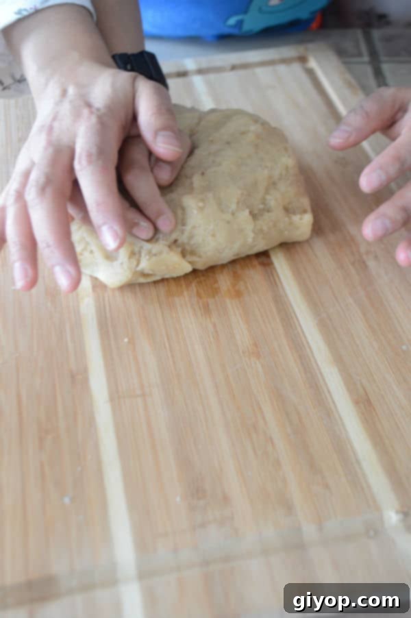 A hand kneading dough on a wooden board