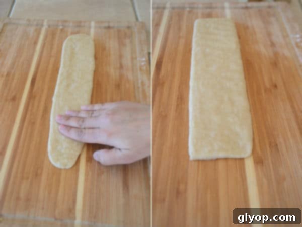 A wooden cutting board, with pieces of dough and hand
