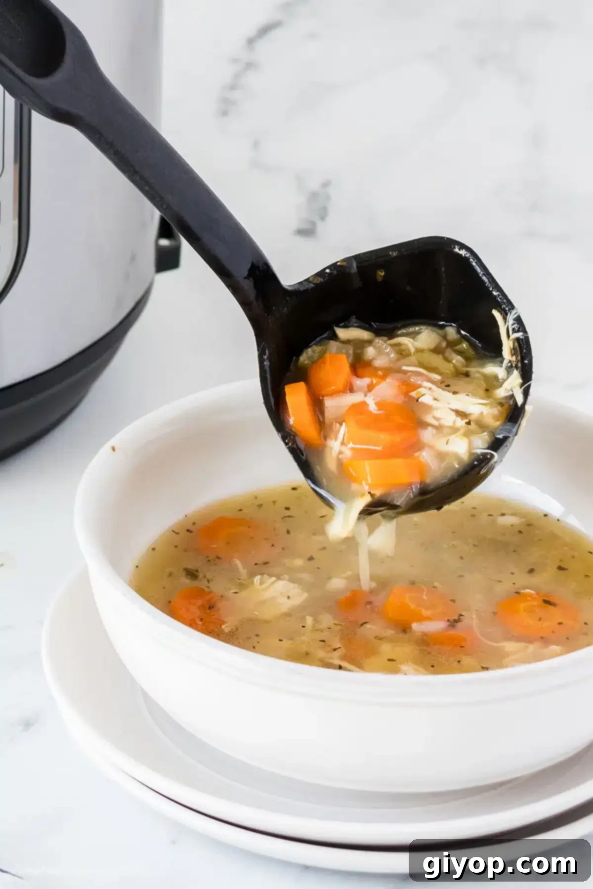 Hearty Instant Pot Chicken and Rice Soup 7 A ladle with chicken soup pouring into a serving bowl.