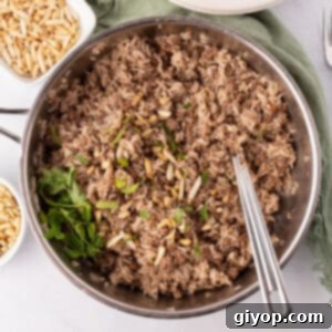 Savory Spiced Hashweh 2 A large skillet of ground beef and rice with a spoon.
