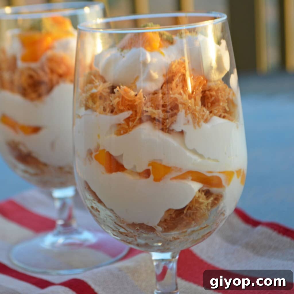 Two tall glasses with mango kunafa parfaits, layered with cream and fresh mango chunks.