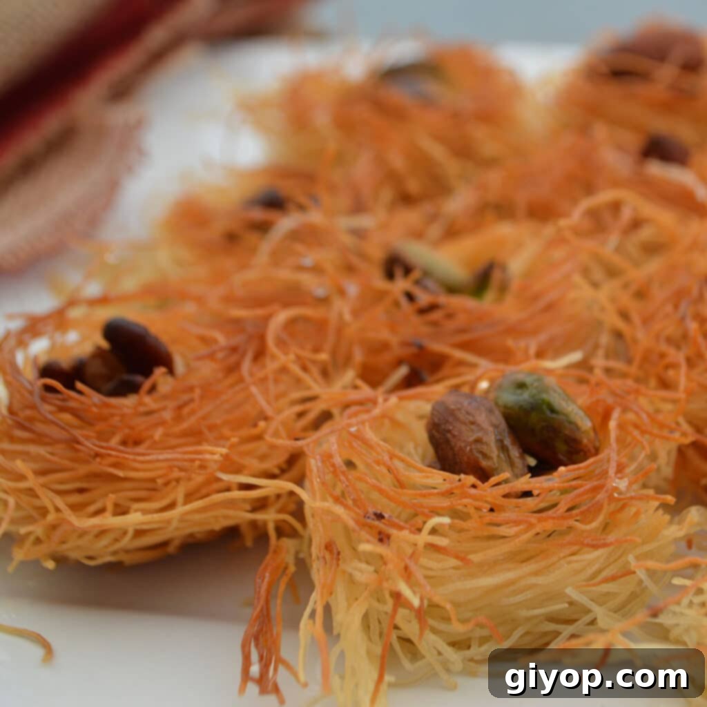 Delicate Kunafa nests filled with various nuts on a white plate, showcasing intricate details and golden color.