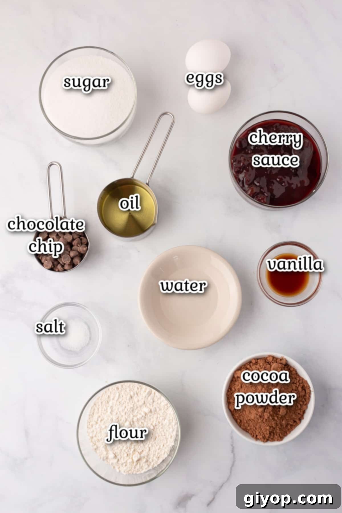 Assortment of Black Forest Brownie ingredients laid out on a kitchen counter, including oil, sugar, eggs, cocoa powder, and cherries.
