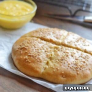 A beautifully baked Moroccan bread, Khobz, on parchment paper, next to a knife, ready for serving.