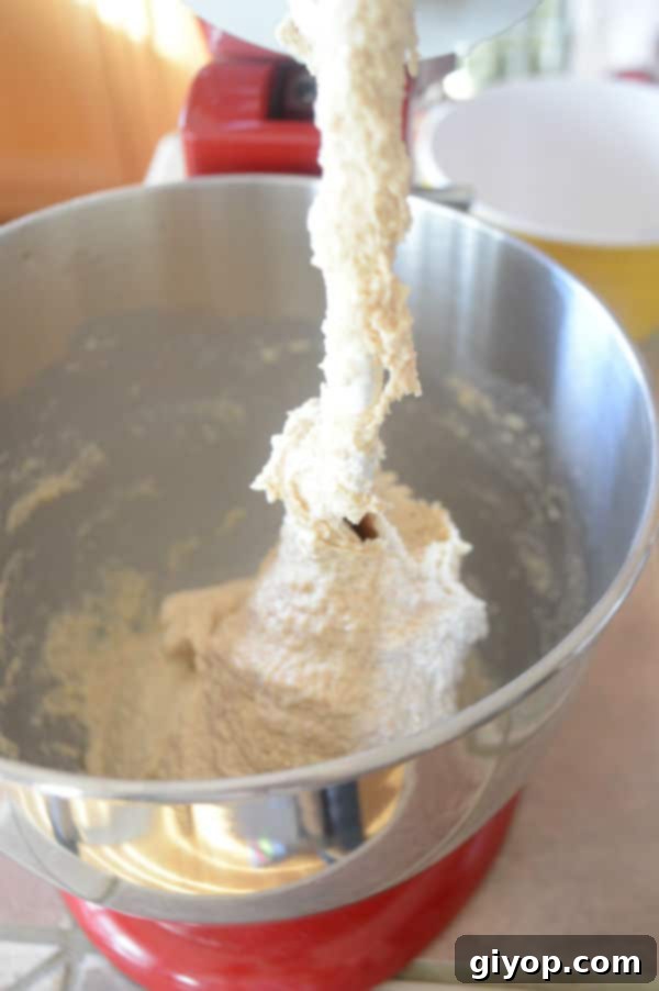 A metal mixing bowl showing a fairly sticky dough that has just formed after adding water, indicating proper hydration.