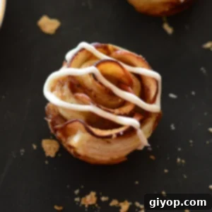 A single baked apple rose on a dark surface, showcasing its delicate layers and golden-brown pastry.
