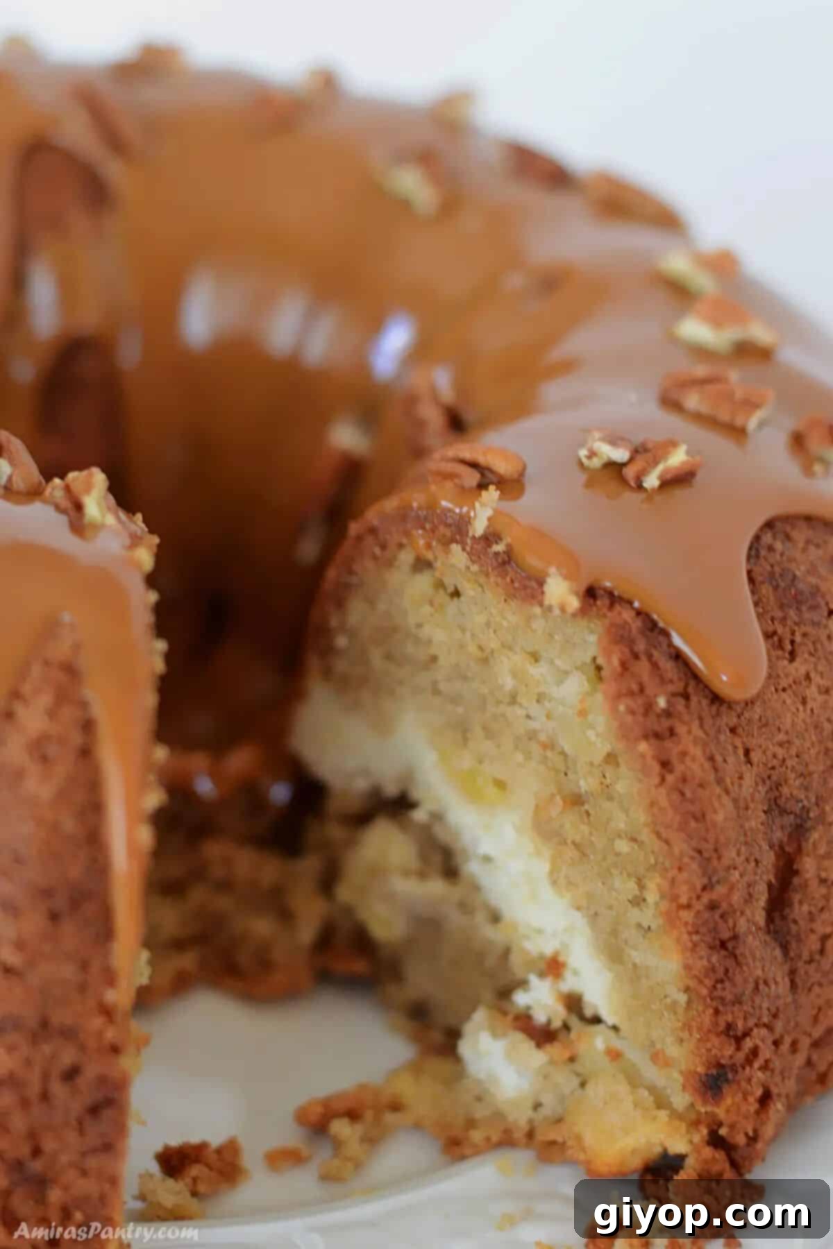 A slice of apple bundt cake on a white plate, showcasing its moist texture and the lovely cream cheese swirl within.