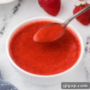 Velvety Strawberry Sauce 2 Strawberry coulis in a white bowl with a spoon.