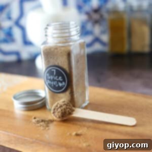 Arabic Seven Spice Blend 2 A glass jar with arabic spices on a wooden cutting board.