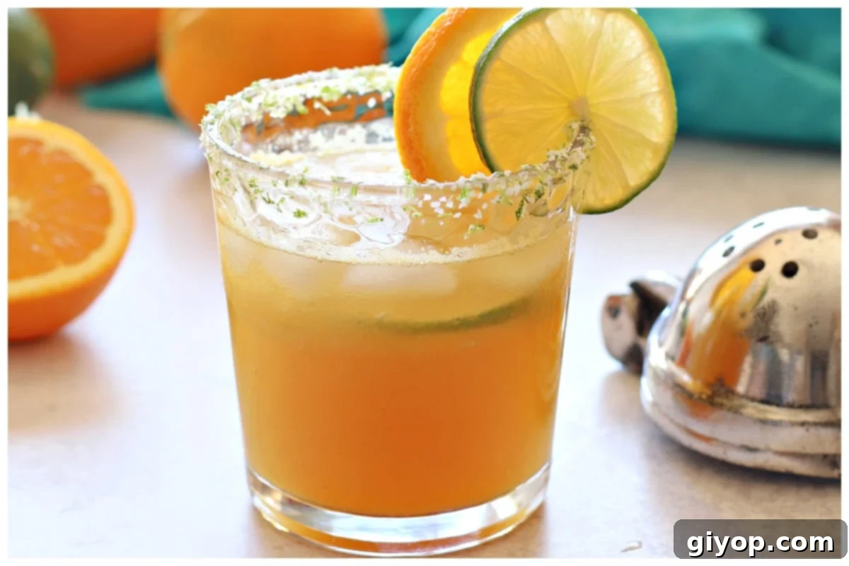 Margarita mocktail in a glass with lime and orange on the back.
