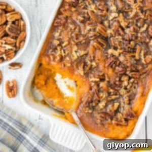 An overhead view of a cracker barrel sweet potato in a white casserole with a spoon.