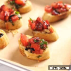 Crispy bread slices on a baking sheet, beautifully topped with fresh tomato bruschetta, ready to be served.