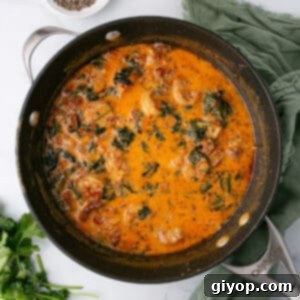 Tuscan shrimp in creamy sauce in a dark skillet with green cloth on the side.