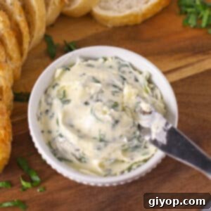 A butter knife in a bowl with garlic butter, ready to be spread.