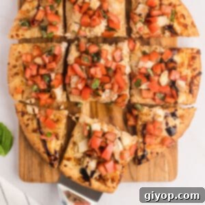 An overhead image of bruschetta pizza with a piece pulled out.