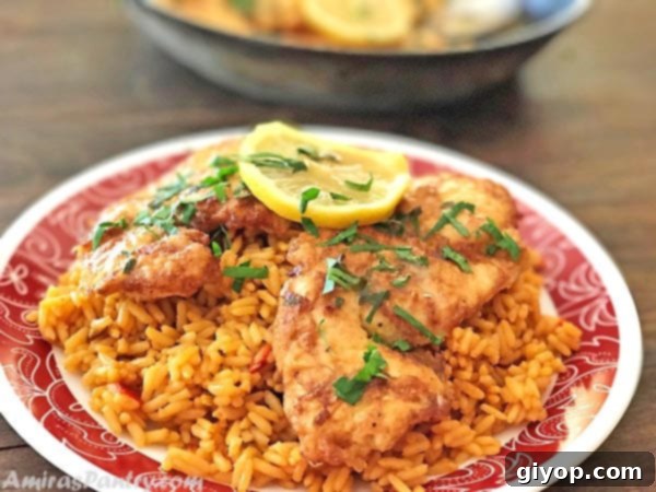 Flavorful Chicken Francese No Wine Required 6 Plated Chicken Francese cutlets resting on a bed of fluffy white rice, elegantly garnished with fresh chopped parsley and a lemon wedge.