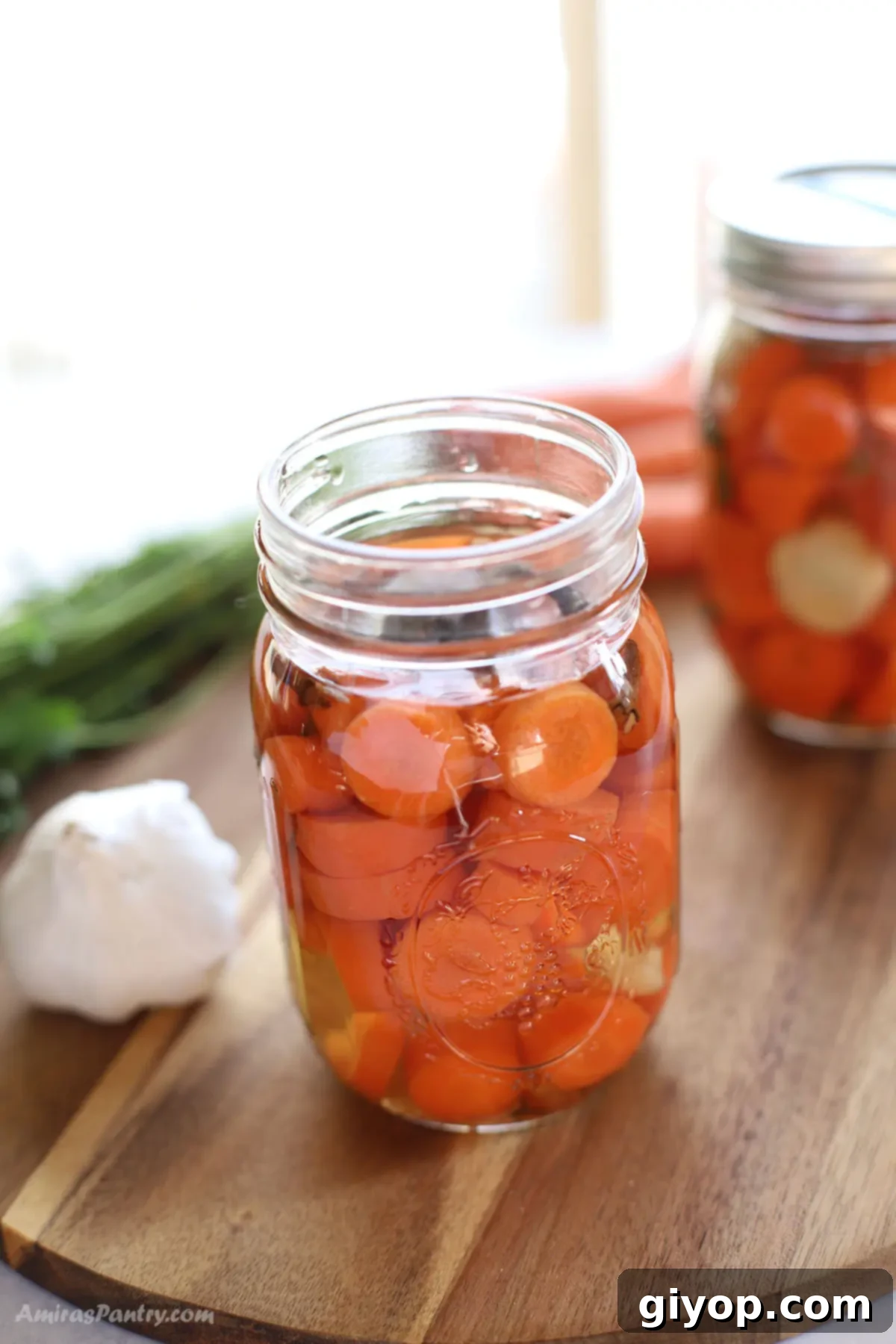 A jar of freshly made quick pickled carrots opened, with another closed jar in the background, showcasing their vibrant color and inviting appeal.