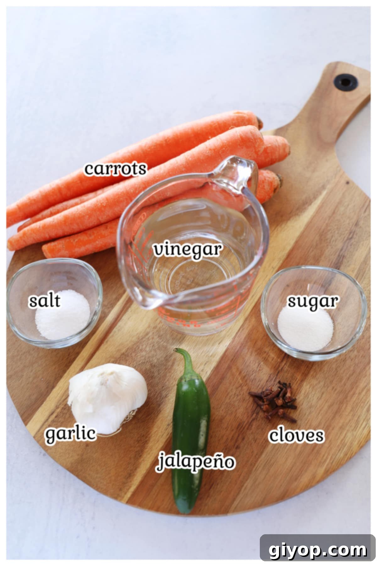 A selection of fresh ingredients neatly arranged on a rustic wooden board, ready for making pickled carrots.