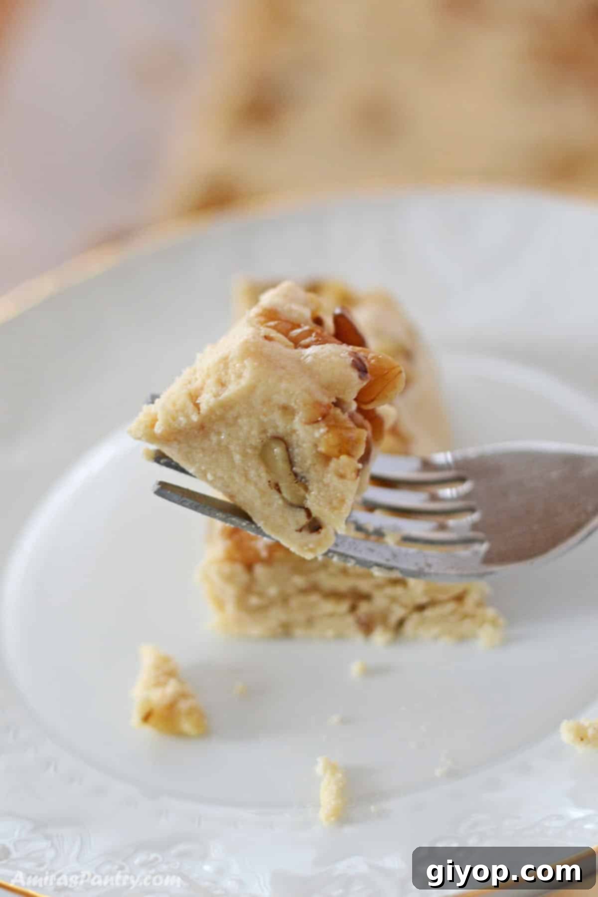 A fork holding a piece of halva with the rest on a white plate.