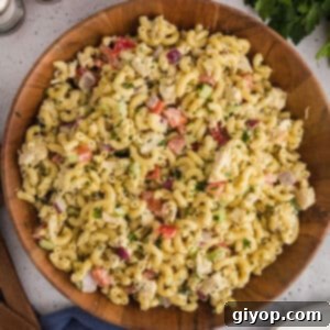 A top-down view of a wooden bowl filled with creamy chicken macaroni salad, ready to be served.