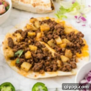 Two beef and potato tacos opened slightly to show inside, showcasing the crispy potatoes and savory beef filling.