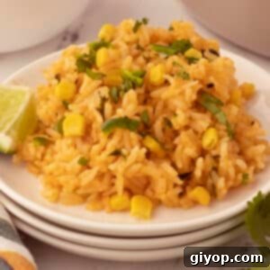 Fiesta Corn Rice 2 A serving of Mexican rice with corn on a white plate, garnished with cilantro and lime wedges.