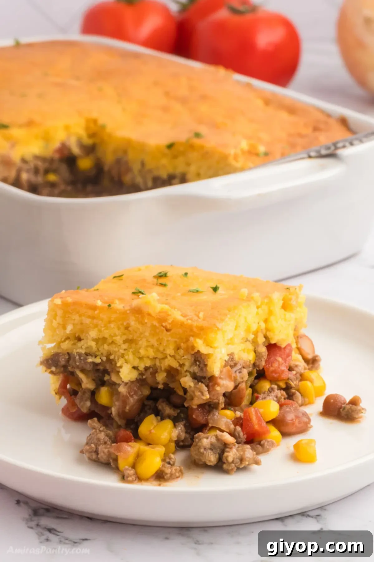 A close-up image of a savory cornbread casserole on a pristine white plate, showcasing its golden crust and delicious filling.