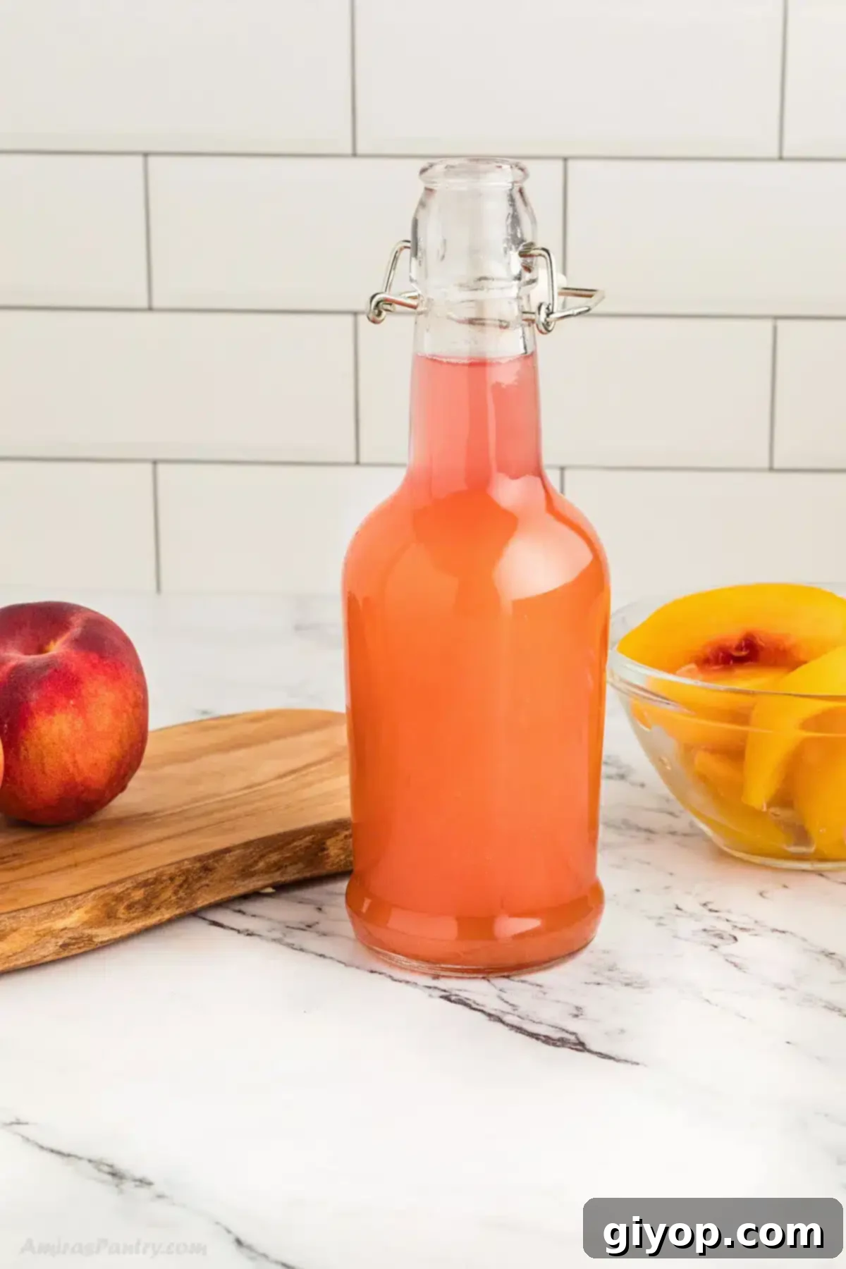 Homemade peach simple syrup in a clear glass bottle, surrounded by fresh, ripe peaches on a rustic wooden surface, evoking a warm summer day.