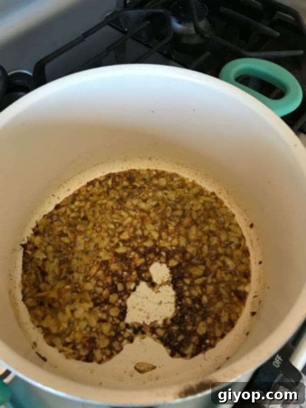 Sauteeing onion, garlic and spices in oil in a deep pot.