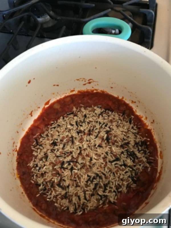 Wild rice being added to the pan with the other ingredients 