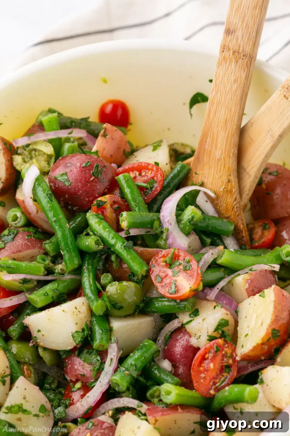Zesty Italian Potato Salad 2 A close up on a bowl with potato salad with a wooden spoons.