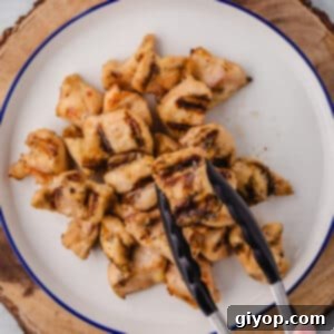 Savory Grilled Chicken Bites 2 A kitchen tonge with a piece of grilled chicken nuggets, showing the perfect grill marks.