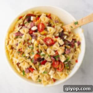 A white bowl with Italian pasta salad garnished with fresh parsley.