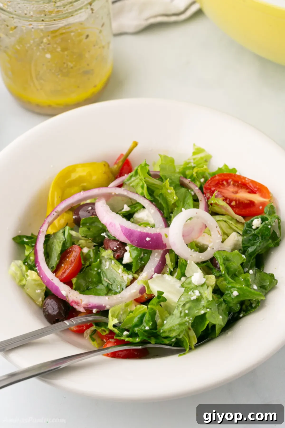 Greek salad in a white bowl with a fork.