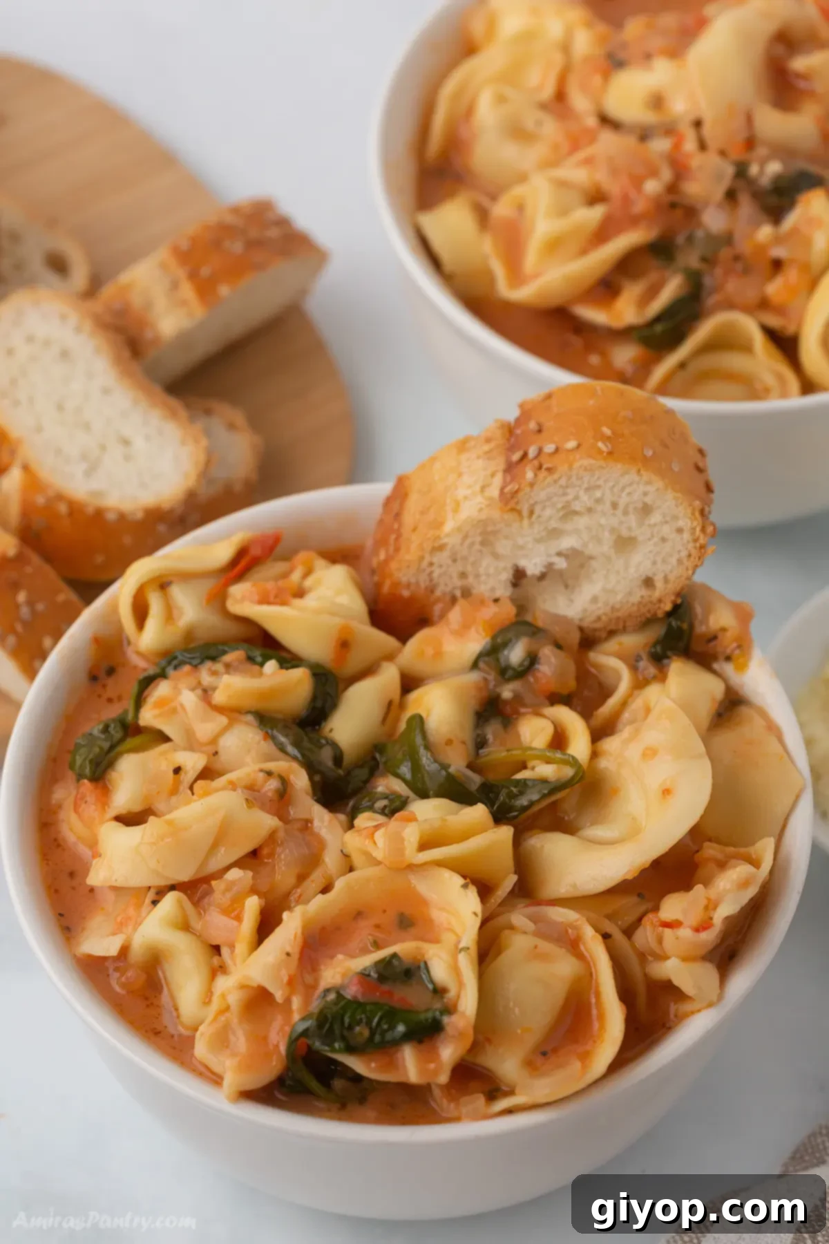 Effortless Instant Pot Soups 5 A bowl of tortellini soup with a piece of bread in it.