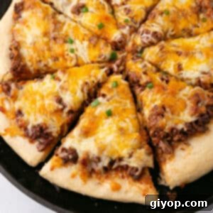 An overhead image of a pizza with a slice pulled out, showing the delicious Sloppy Joe topping and melted cheese.