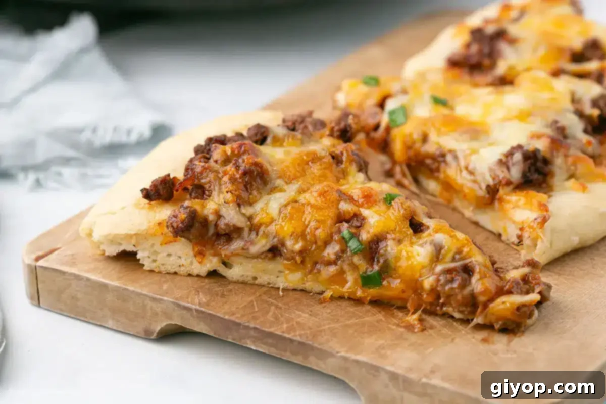 A delicious slice of Sloppy Joe Pizza placed on a rustic wooden board, ready to be enjoyed.
